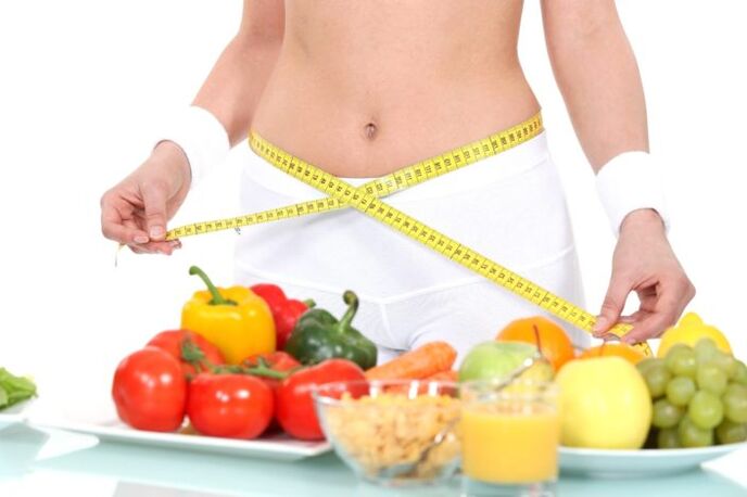 gadis mengukur pinggang dengan latar belakang bahan makanan